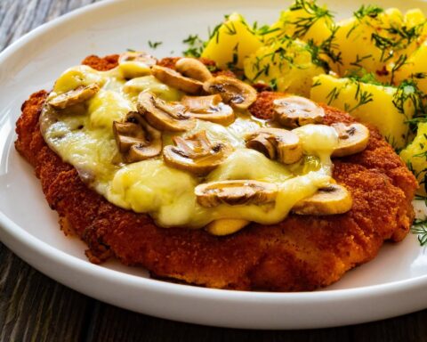 Panierowany kotlet zapiekany serem i pieczarkami, podany z ziemniakami z koperkiem